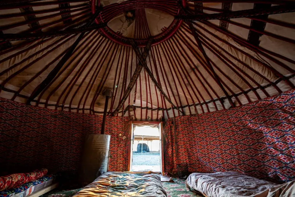 Interior of a bell tent decorated with colorful fabric and bedding.