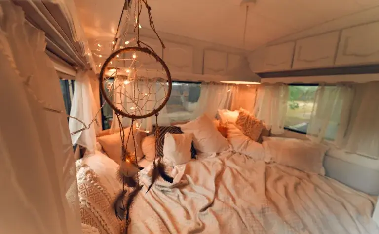 Boho style camp bed with pillows and a dream catcher.