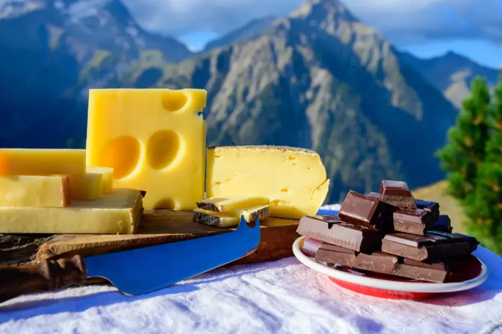 Cheese, nuts and chocolates with a winter mountain in the background.