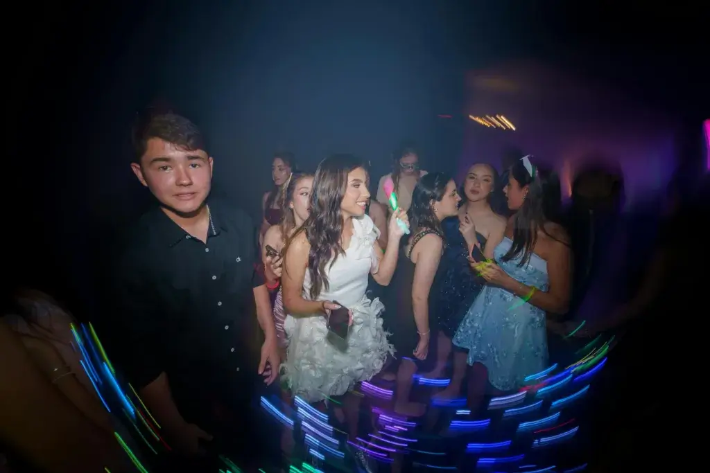 A group of teenagers enjoying a vibrant party with colorful lights and playful atmosphere.