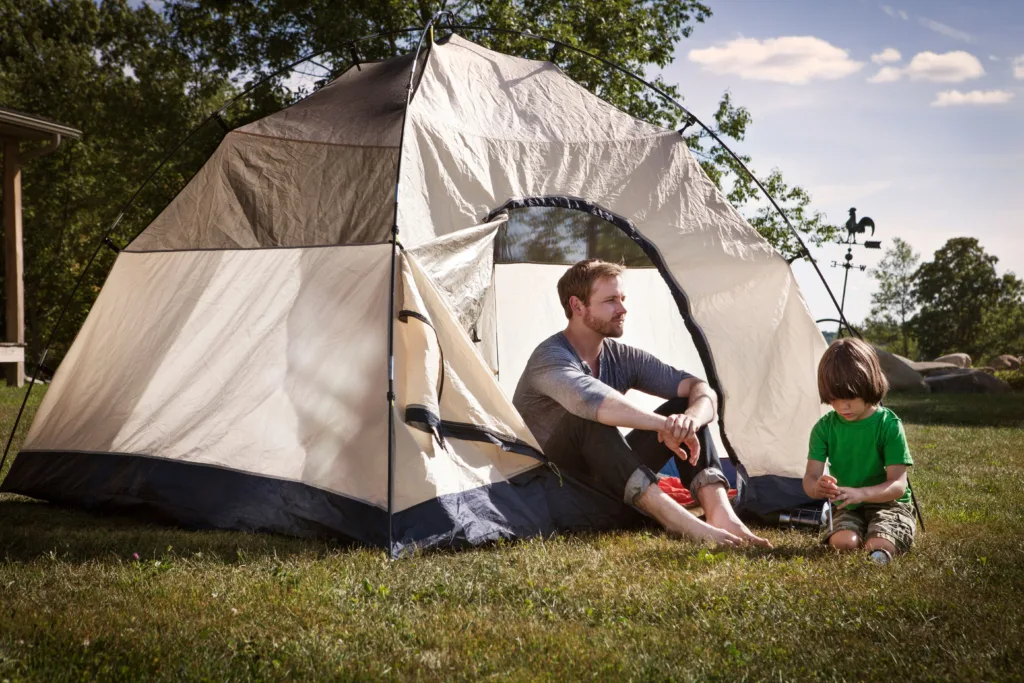Father and son backyard camping in a tent.