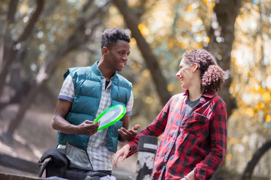 A man and woman playing frisbee in a park.