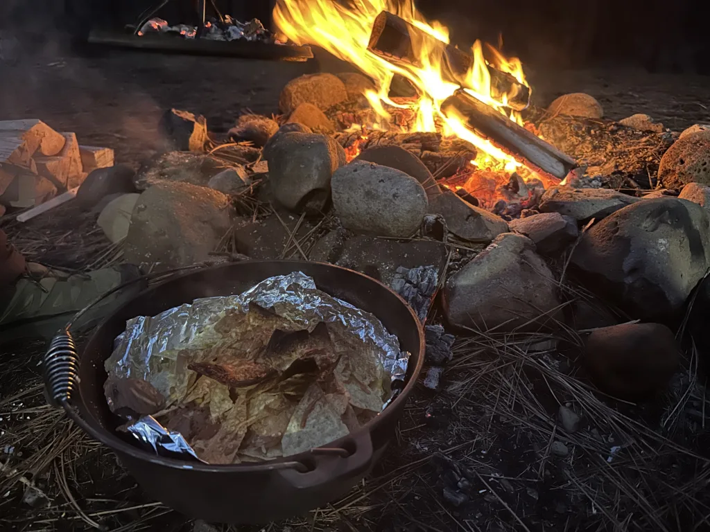 Campfire nachos in a dutch oven being made on a campfire.