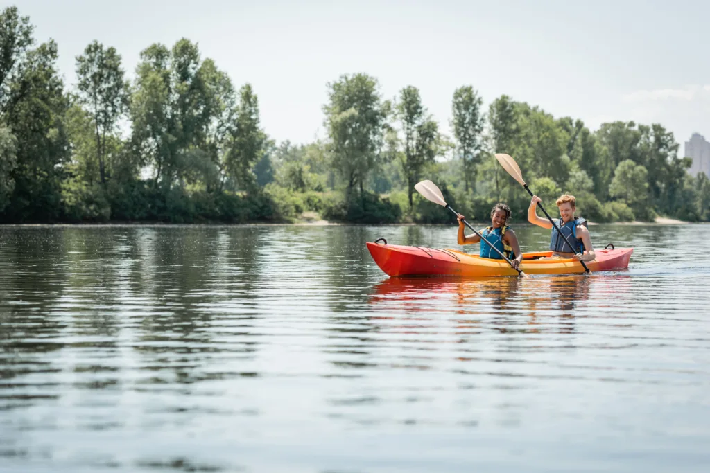 Woman kayaking on a calm lake with trees in the background.