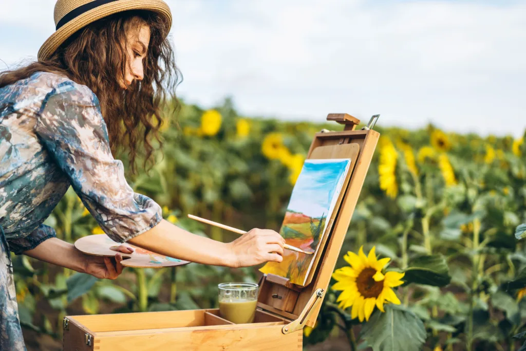 Woman painting in a field of sunflowers.