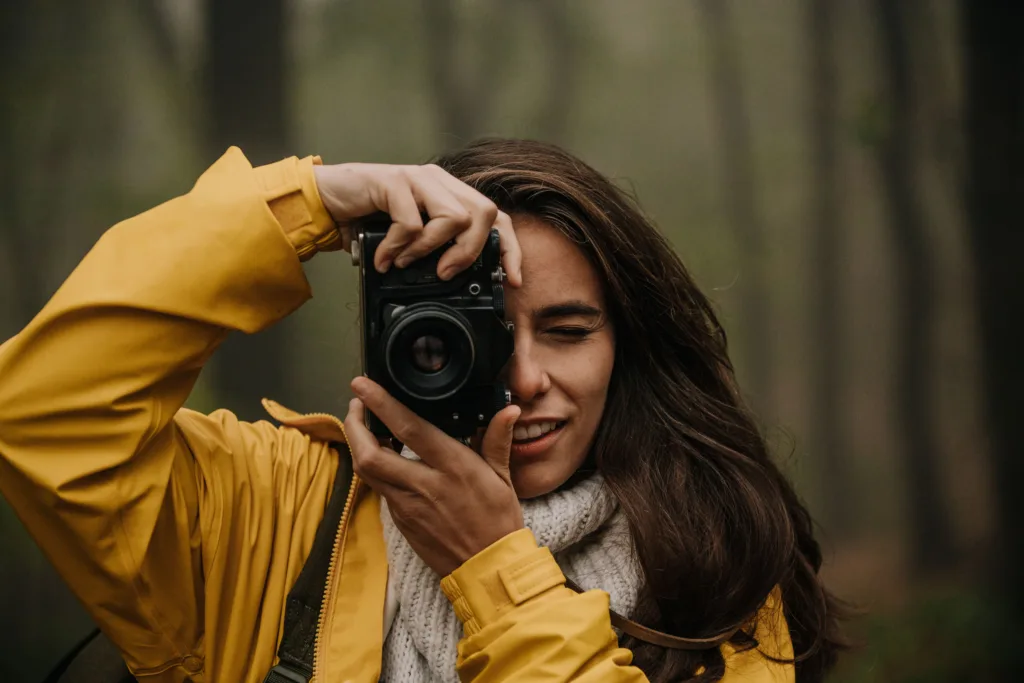 Woman out in nature with a camera taking a picture.