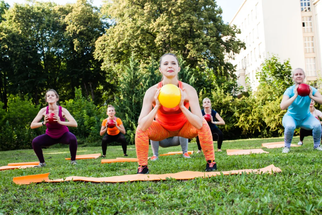 Women practicing outdoor fitness in the park with medicine balls.