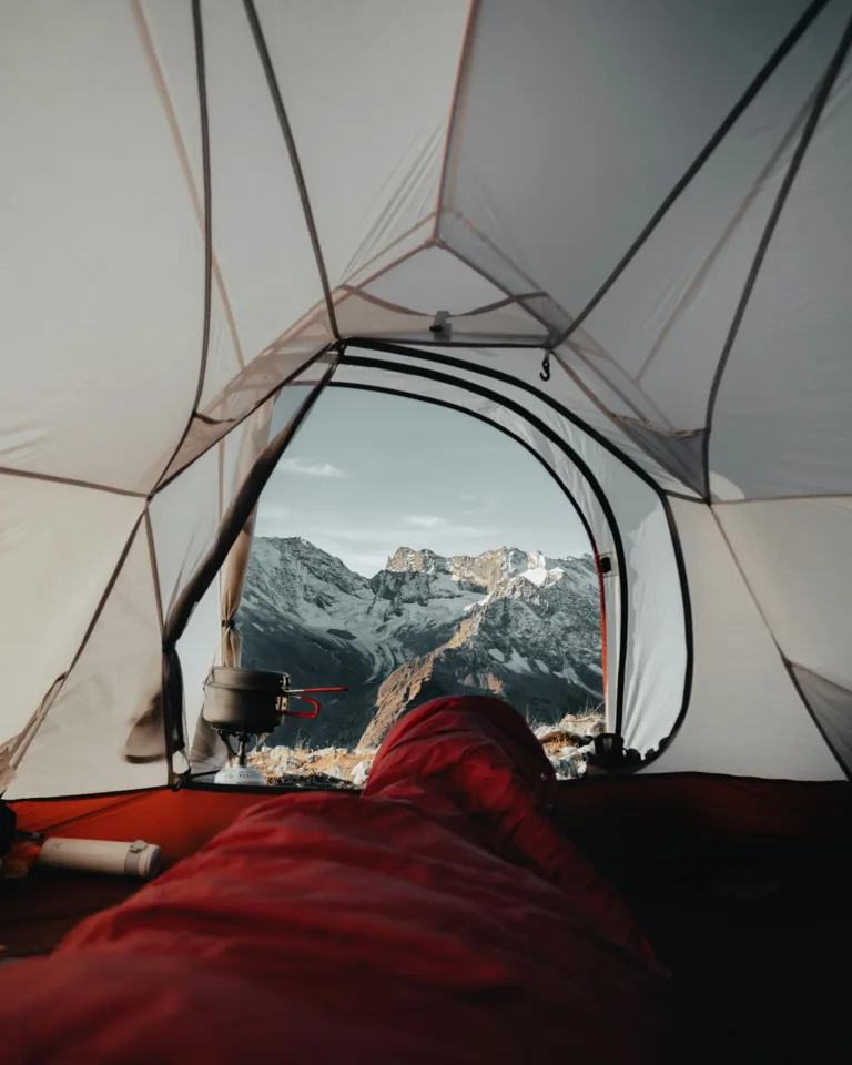 Experience the serene beauty of snowcapped mountains from a cozy tent setting, perfect for adventure seekers.