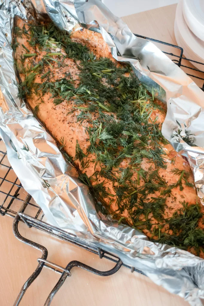 Freshly baked salmon fillet with dill seasoning wrapped in aluminum foil, ready for serving.