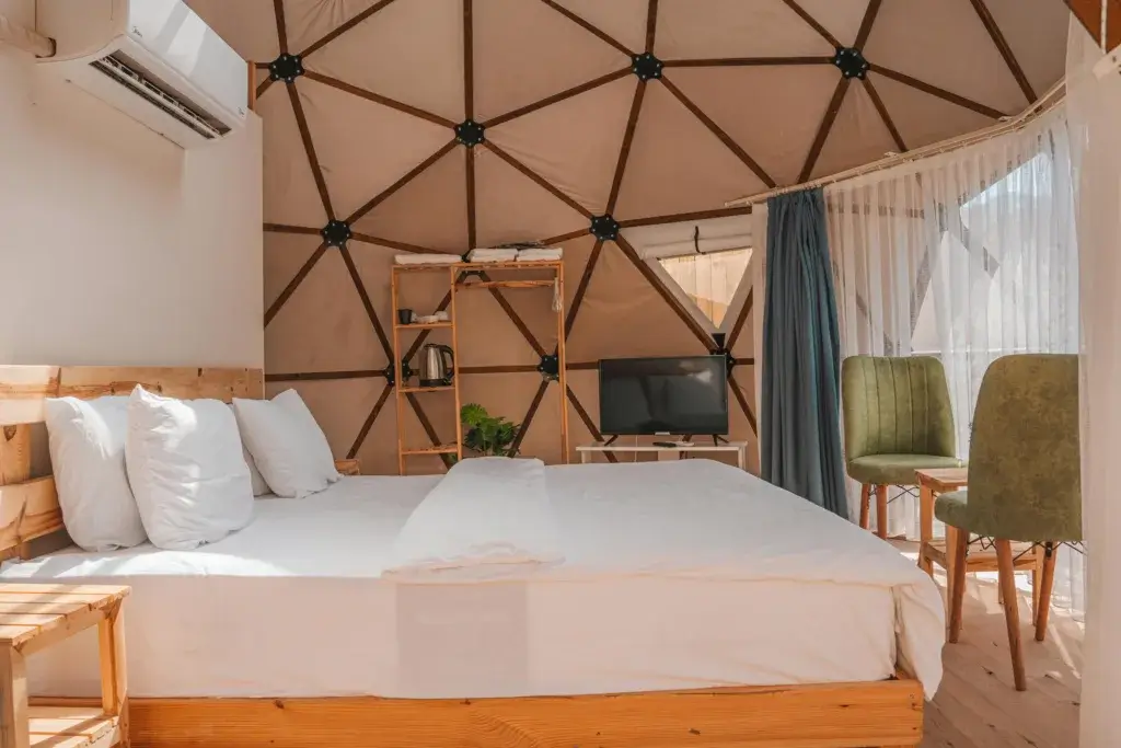 Modern dome accommodation interior featuring a bed, air conditioning, and seating area in Kemer, Türkiye.