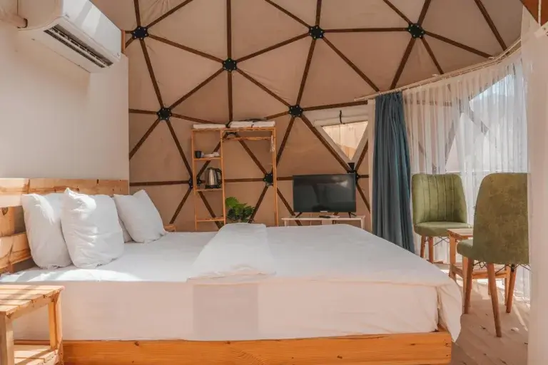 Modern dome accommodation interior featuring a bed, air conditioning, and seating area in Kemer, Türkiye.