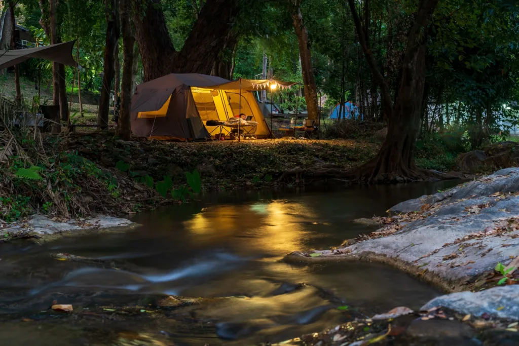 Glamping tent at night next to a beautiful river.
