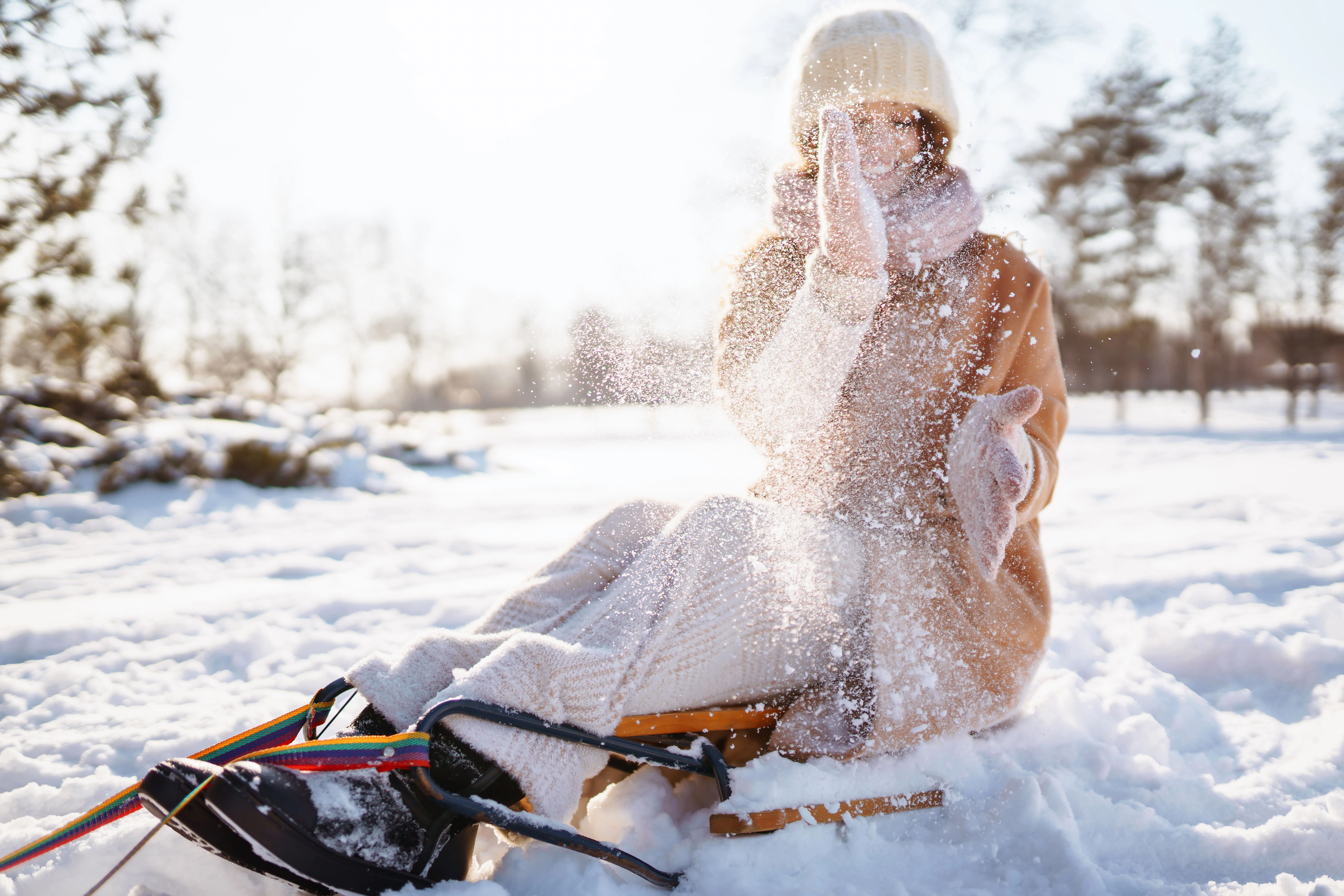 Stylish young woman on a sled playing in the snow.