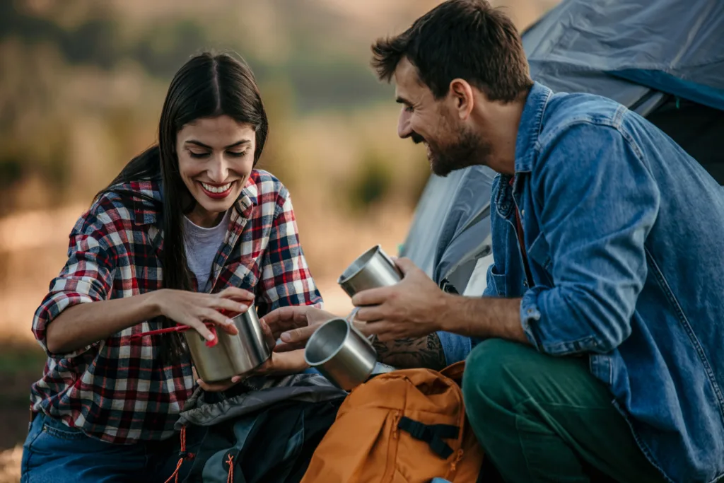 Young couple camping and having a drink.