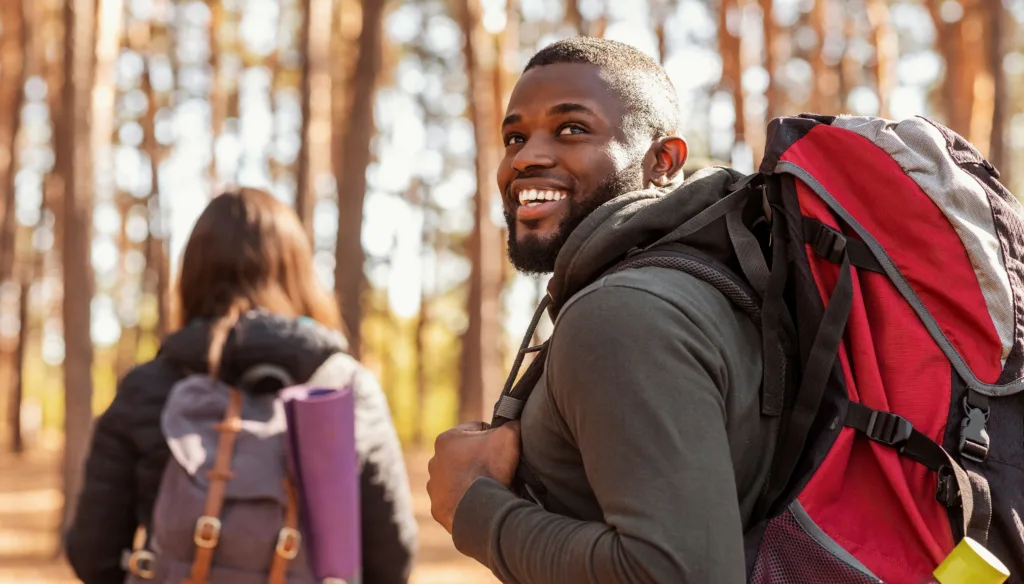 Young couple hiking, man looking back at the camera smiling.