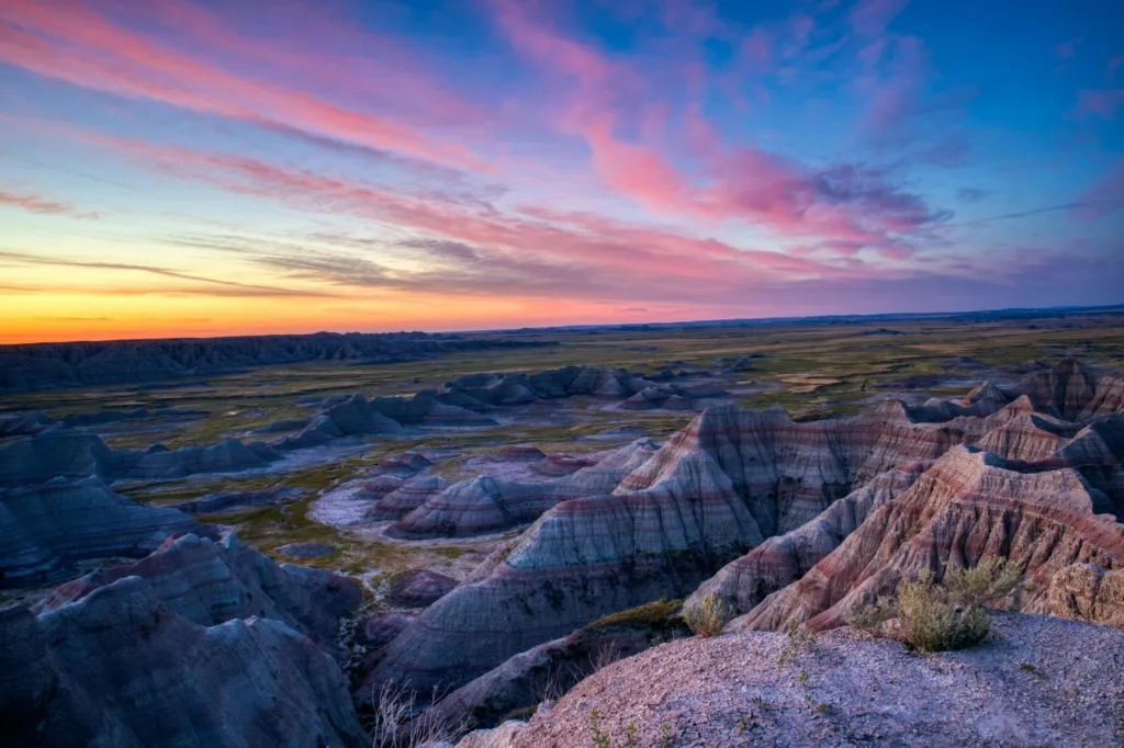 Breathtaking view of Badlands National Park with dramatic rock formations and colorful sunset skies.