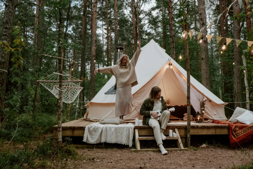 Couple enjoying a glamping experience with music and dancing in a forest setting.
