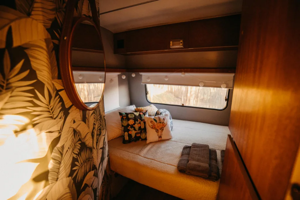 Stylish camper van interior with cozy bed and decorative pillows, offering a warm and inviting ambiance for travel enthusiasts.