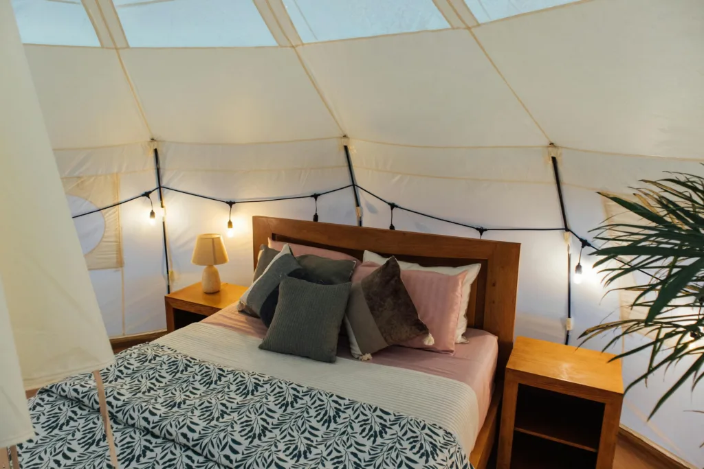 Stylish glamping tent interior with cozy bed setup, ideal for a nature retreat.