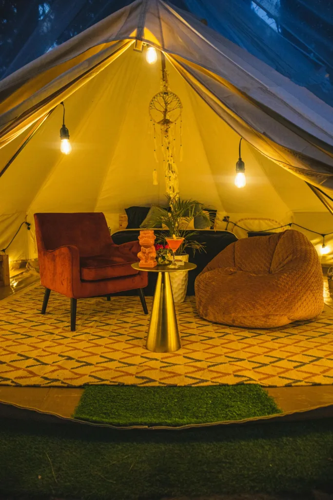 Warm and inviting glamping interior with chairs, lights, and decorative elements in a tent.