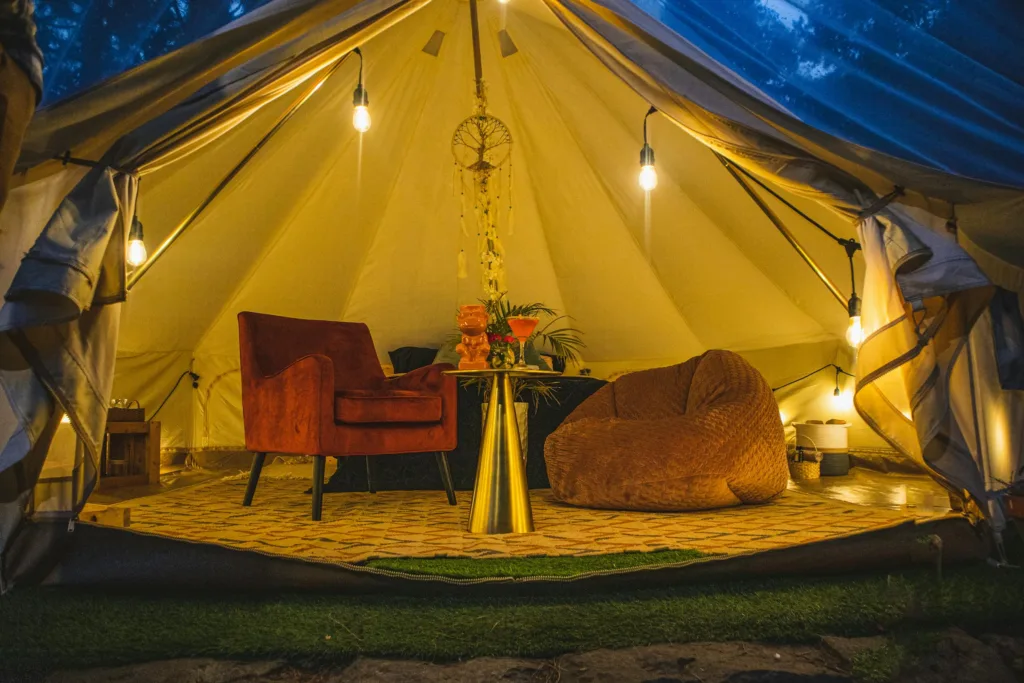 Warmly lit glamping tent interior with plush seating, creating a cozy escape in Cuenca.