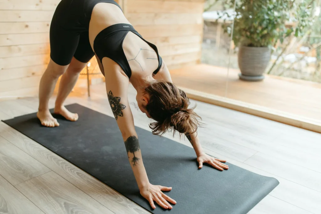 Woman in activewear doing yoga on a mat indoors, focusing on flexibility and fitness.