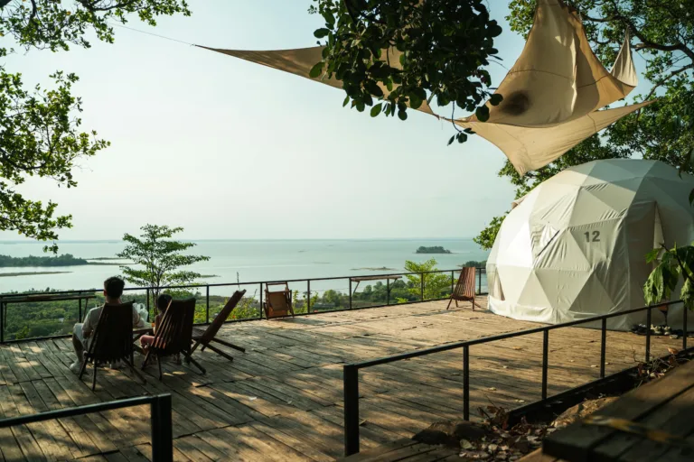 Relaxing outdoor deck with ocean view featuring a geodesic tent and deck chairs under shade.