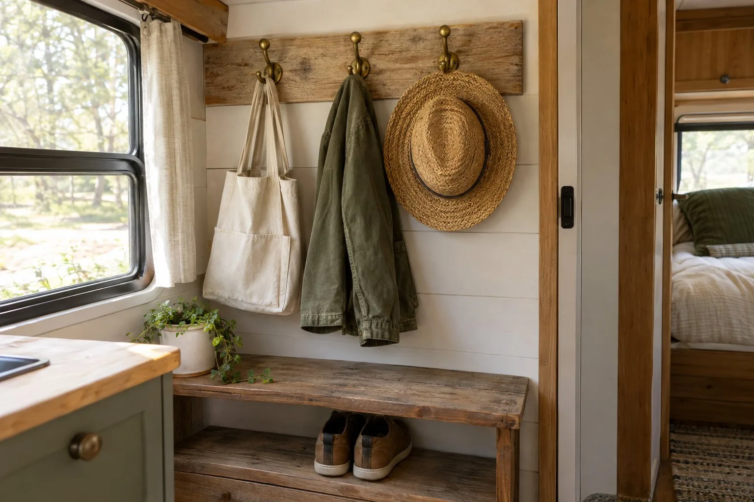 Wall hooks holding a jacket, tote bag, and hat in a camper entryway.