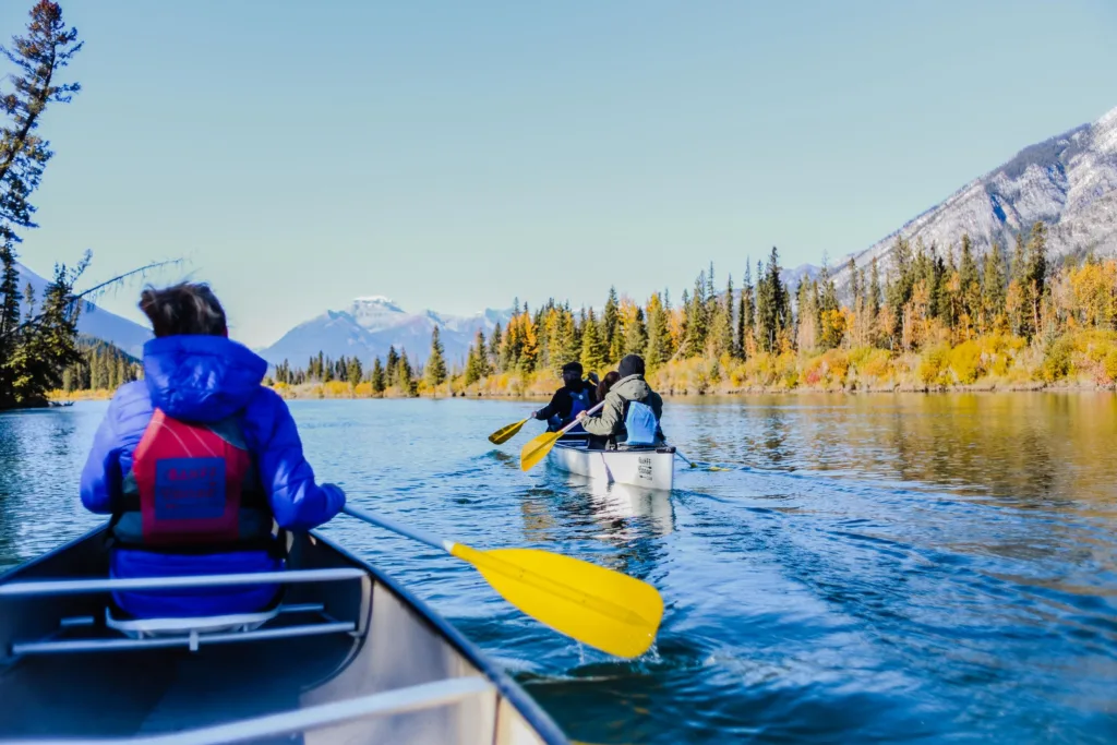 Adults kayaking on a serene lake surrounded by mountains and trees, enjoying adventure in nature.