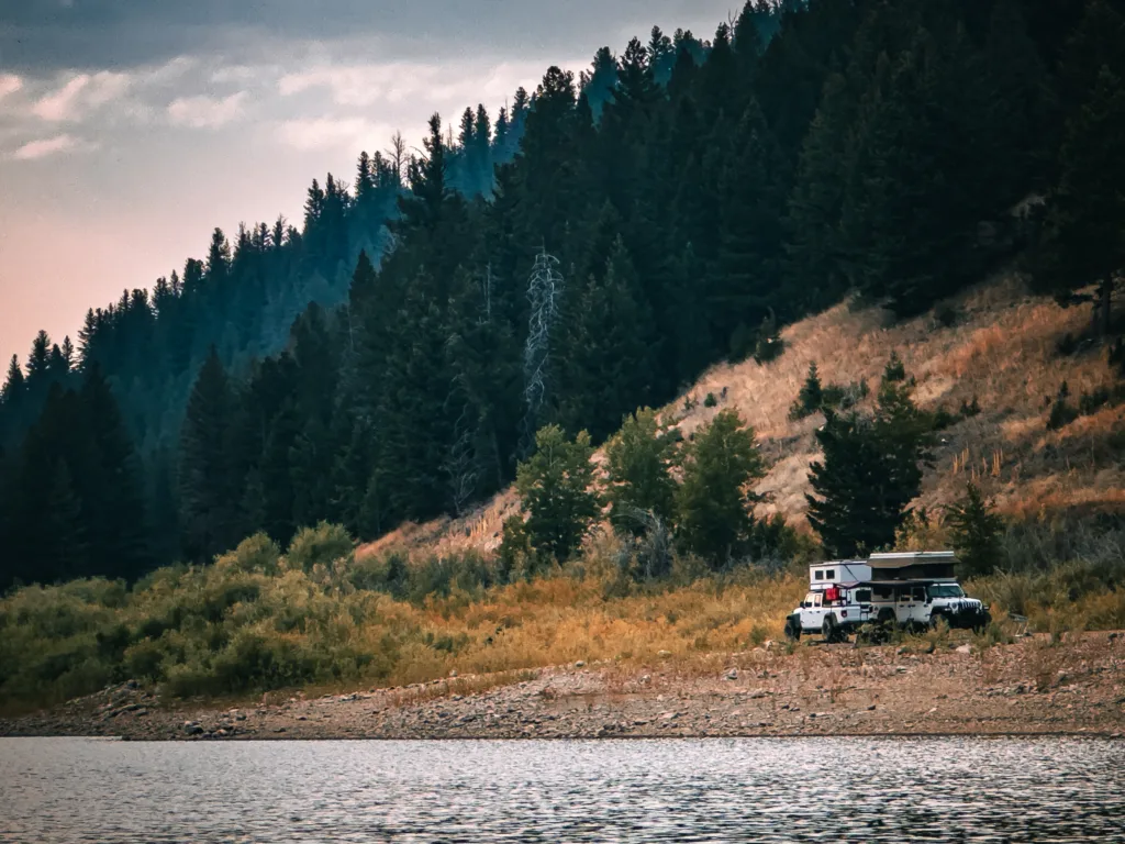 Two Jeep Gladiators with campers parked on public land next to a lake.