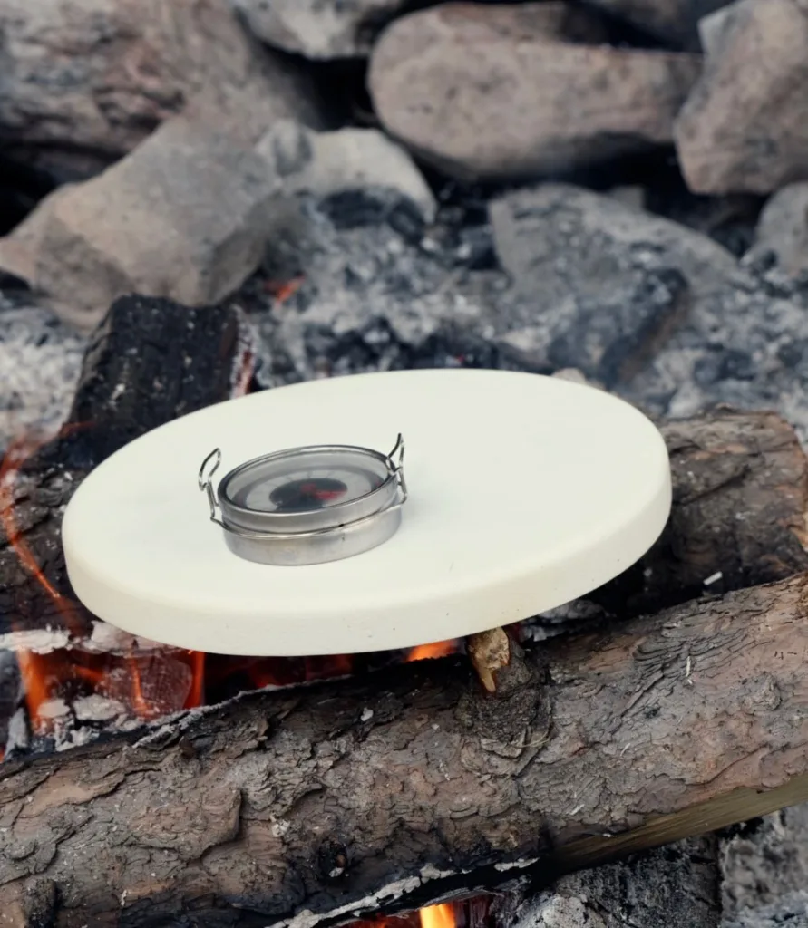RockPot and thermometer being heated on a campfire.