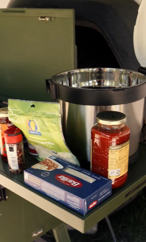 Rockpot and ingredients for lasagna incucing marinara sauce, cheese and noodles.