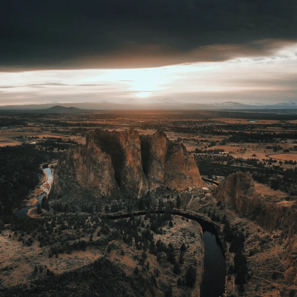 Stunning aerial view of Smith Rock State Park with dramatic sunset lighting and winding river.