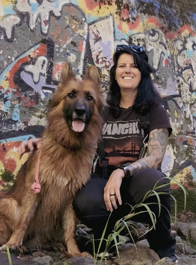 Woman and German Shepherd dog in front of a graffit wall.